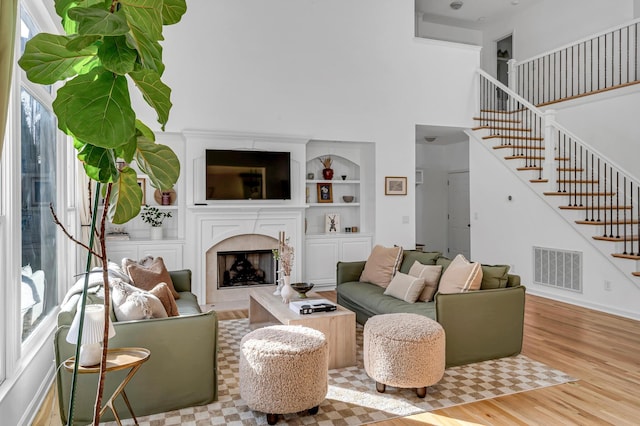 living room featuring a high ceiling, a fireplace, and light hardwood / wood-style floors