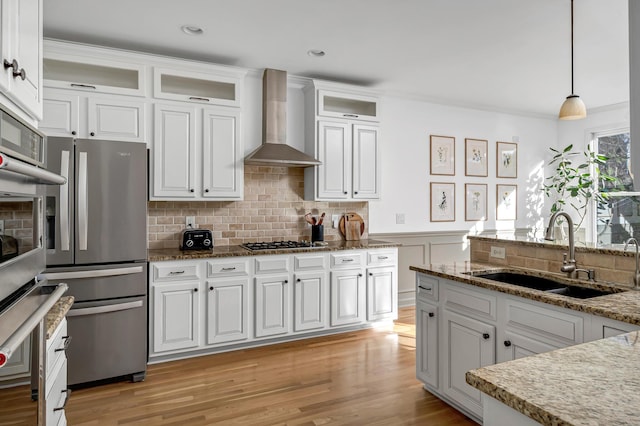 kitchen with sink, wall chimney range hood, and white cabinets