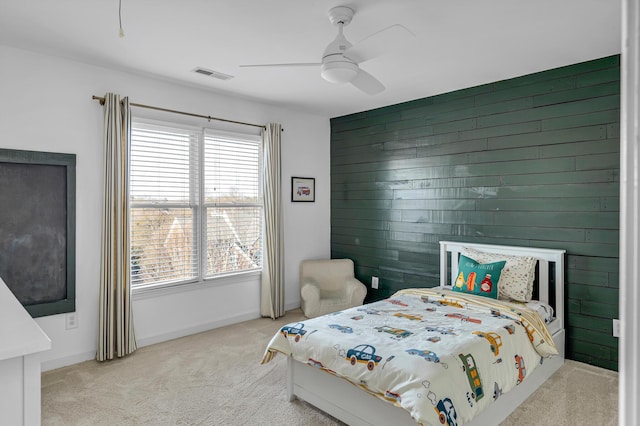 carpeted bedroom with ceiling fan and wooden walls