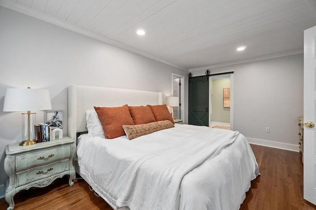 bedroom featuring ornamental molding, a barn door, dark hardwood / wood-style floors, and ensuite bath