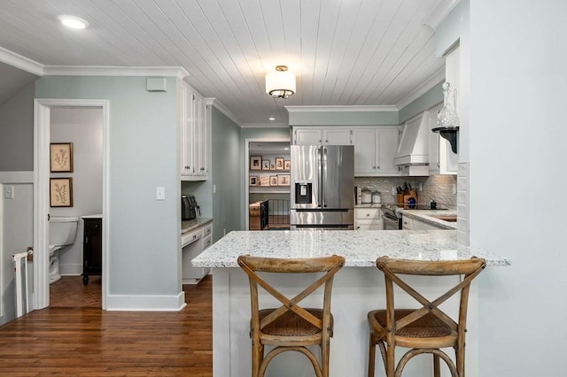 kitchen featuring a breakfast bar, stainless steel appliances, ornamental molding, white cabinets, and custom exhaust hood