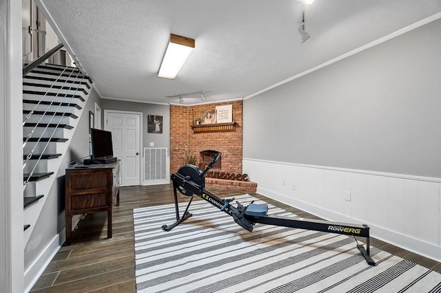 sitting room with dark hardwood / wood-style floors, crown molding, a brick fireplace, track lighting, and a textured ceiling