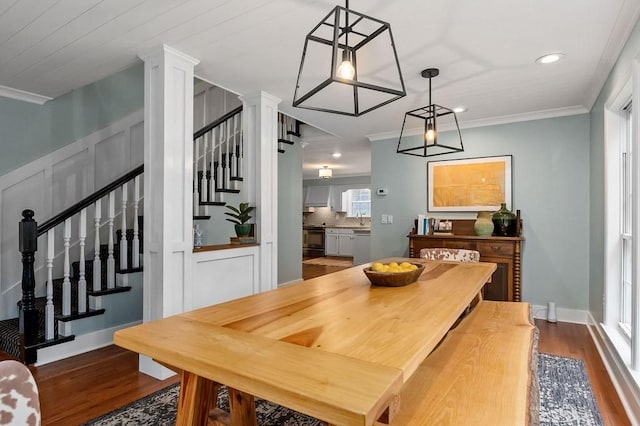 dining room with crown molding, sink, dark hardwood / wood-style floors, and decorative columns