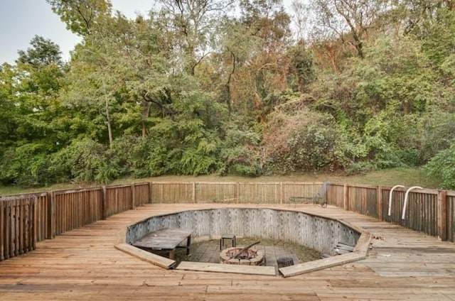 view of swimming pool with a wooden deck and an outdoor fire pit