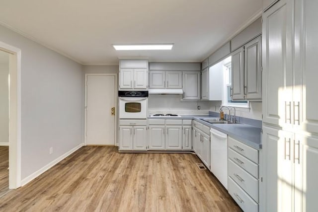 kitchen with gray cabinets, sink, ornamental molding, light hardwood / wood-style floors, and white appliances