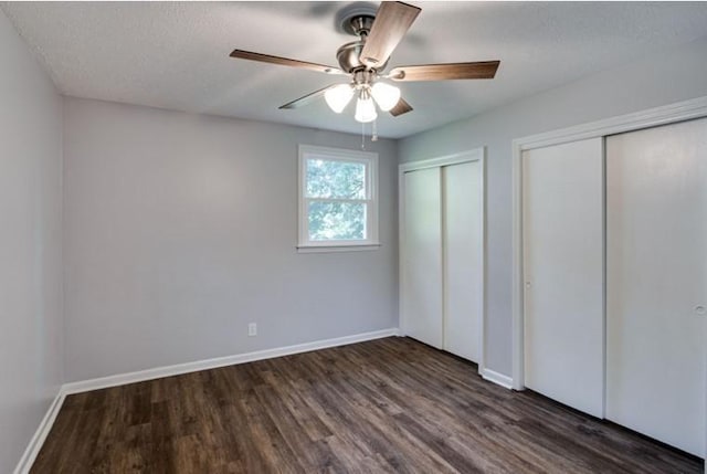 unfurnished bedroom with dark hardwood / wood-style flooring, two closets, a textured ceiling, and ceiling fan