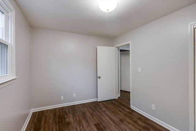 unfurnished room featuring a wealth of natural light and dark hardwood / wood-style floors