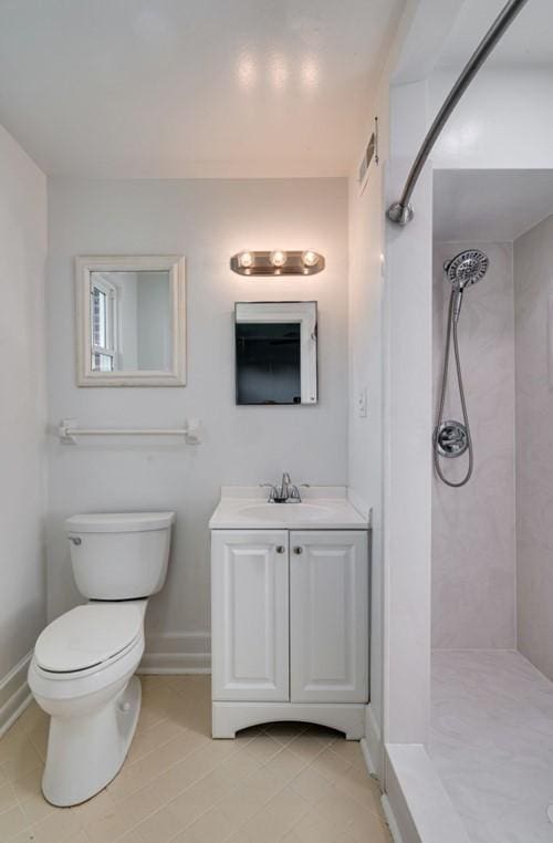 bathroom featuring vanity, tile patterned flooring, toilet, and tiled shower