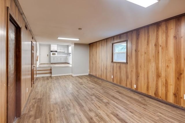 unfurnished living room featuring light hardwood / wood-style flooring and wooden walls