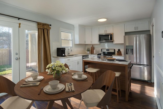 kitchen featuring white cabinetry, backsplash, stainless steel appliances, and a kitchen island