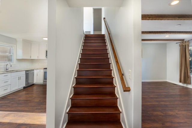 stairs with hardwood / wood-style floors, sink, and beamed ceiling