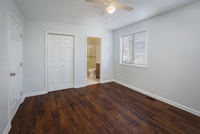 unfurnished bedroom featuring ceiling fan, wood-type flooring, ensuite bathroom, and a closet