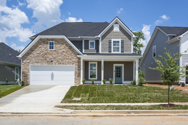 view of front of home with a garage, covered porch, and a front lawn