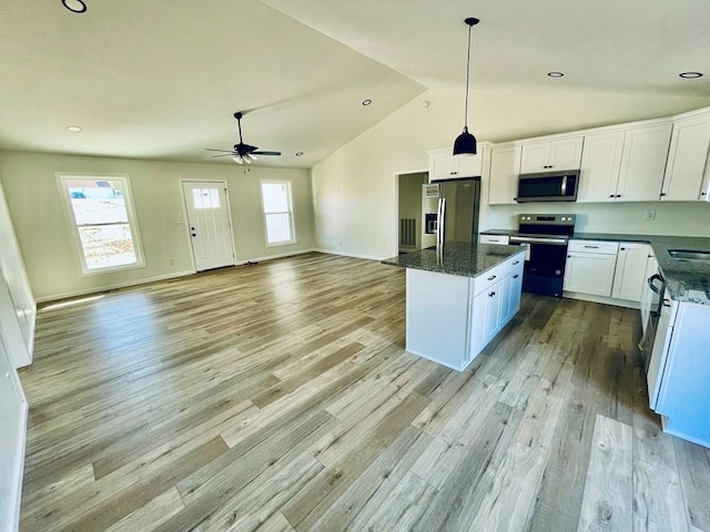 kitchen featuring dark stone countertops, appliances with stainless steel finishes, a kitchen island, and white cabinets