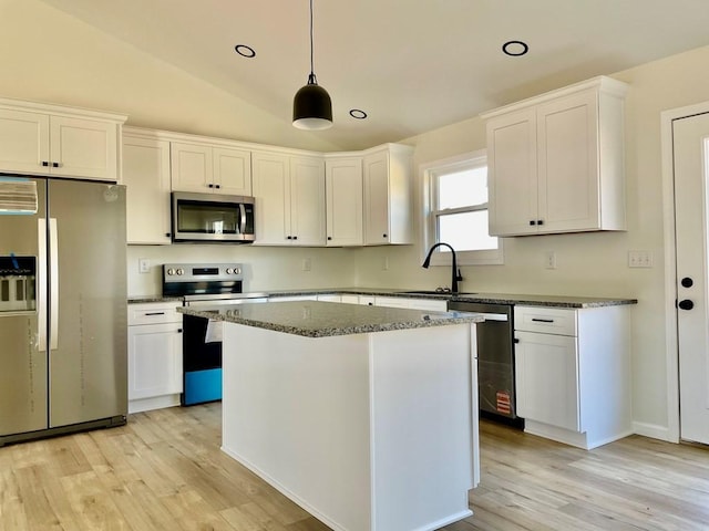 kitchen with sink, vaulted ceiling, stainless steel appliances, and white cabinets