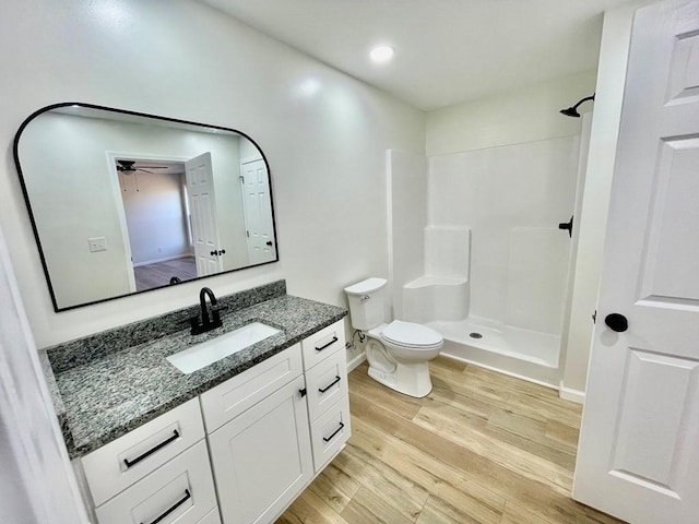 bathroom featuring wood-type flooring, toilet, vanity, and walk in shower