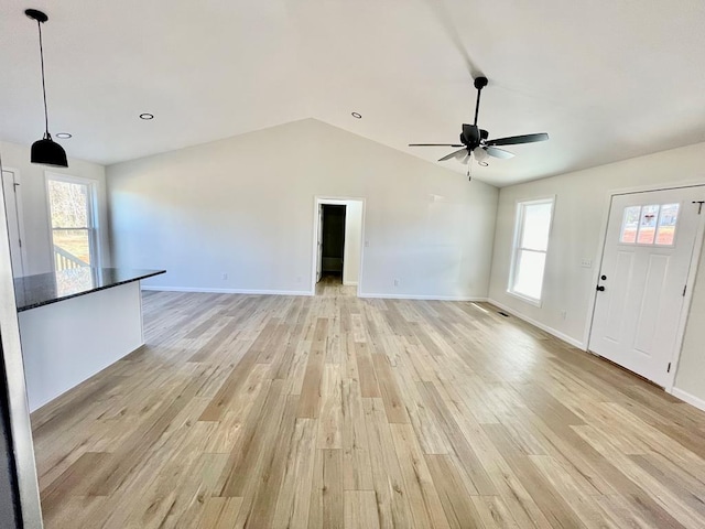 unfurnished living room with ceiling fan, lofted ceiling, and light wood-type flooring