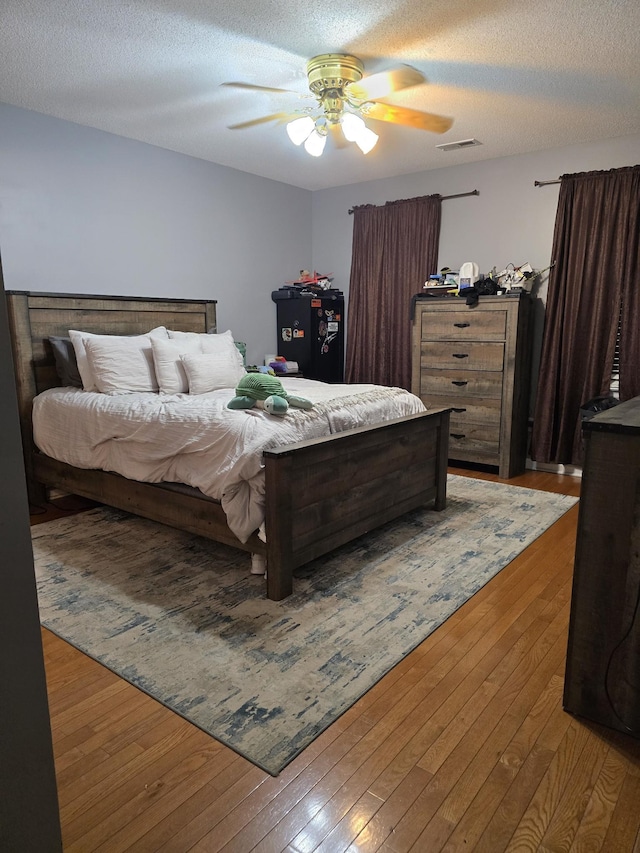 bedroom with hardwood / wood-style floors, a textured ceiling, and ceiling fan