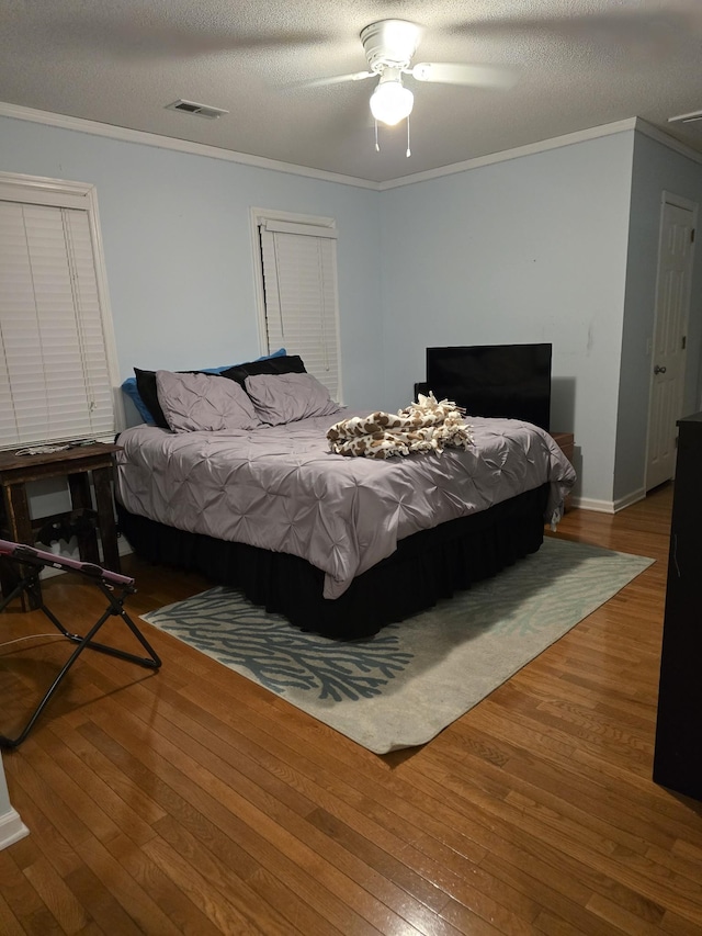 bedroom featuring hardwood / wood-style flooring, ceiling fan, ornamental molding, and a textured ceiling