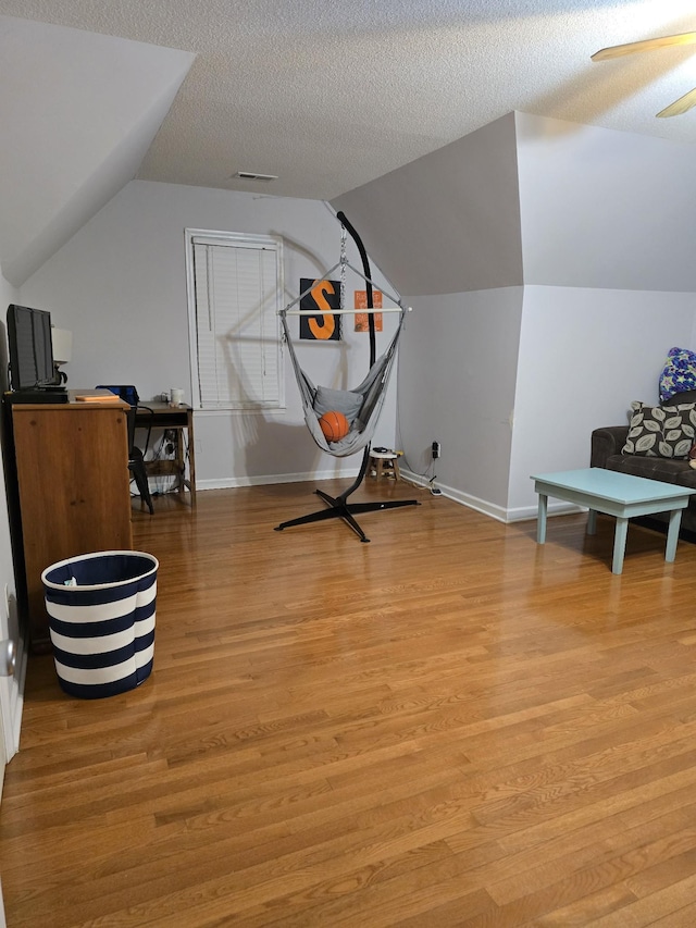 interior space with lofted ceiling, ceiling fan, a textured ceiling, and light wood-type flooring