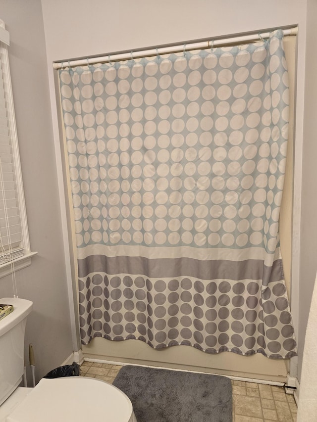 bathroom with shower / tub combo with curtain and toilet