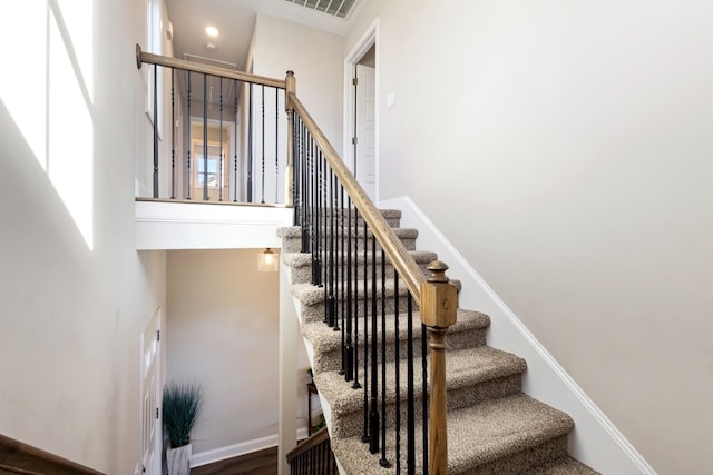 stairway featuring hardwood / wood-style flooring and a high ceiling