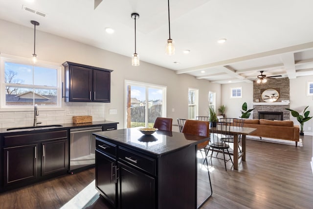 kitchen featuring a kitchen island, sink, a kitchen breakfast bar, stainless steel dishwasher, and beam ceiling