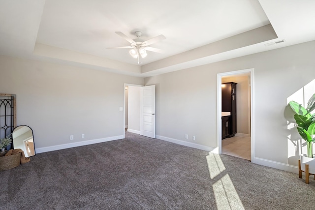 unfurnished room with a tray ceiling, ceiling fan, and carpet