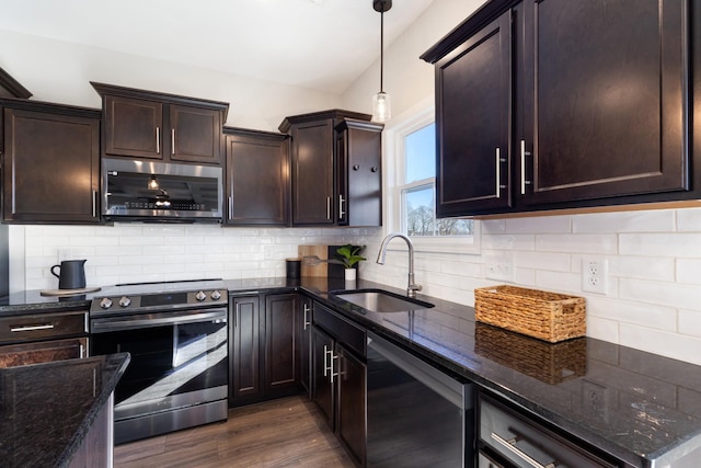 kitchen with sink, dark stone counters, dark hardwood / wood-style floors, pendant lighting, and stainless steel appliances