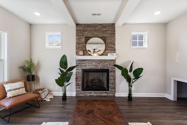 living area featuring beamed ceiling, a fireplace, and dark wood-type flooring