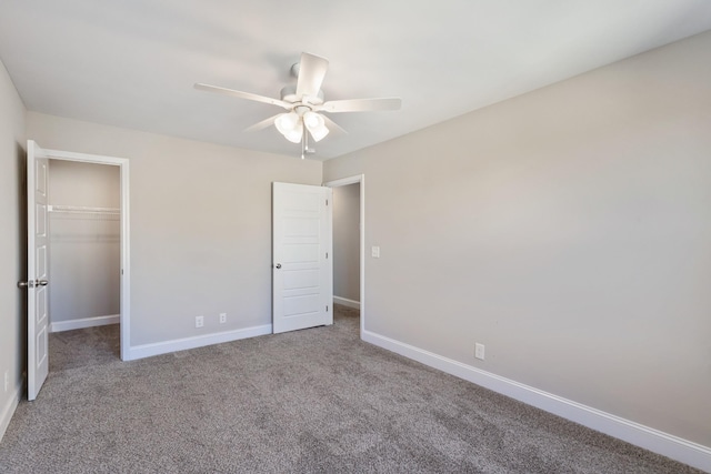 unfurnished bedroom featuring a walk in closet, carpet, ceiling fan, and a closet