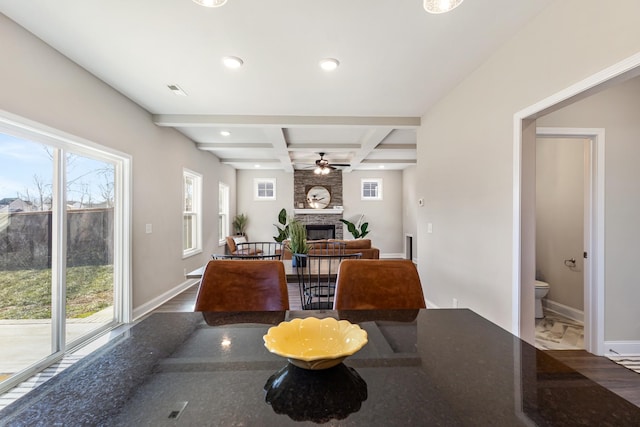 dining space featuring ceiling fan, coffered ceiling, a large fireplace, and beam ceiling