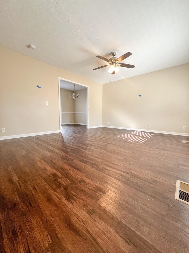 empty room featuring dark hardwood / wood-style floors and ceiling fan with notable chandelier