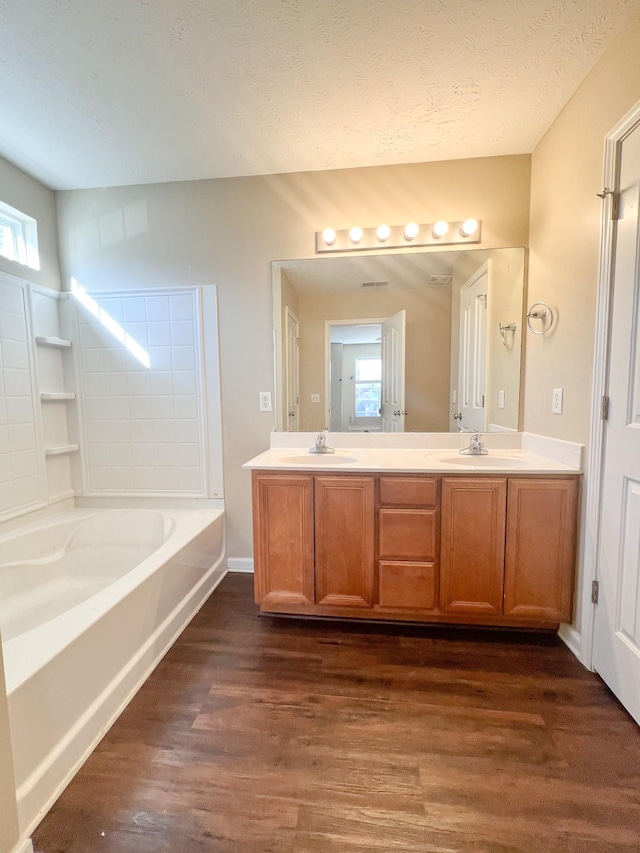 bathroom with wood-type flooring, vanity, a textured ceiling, and  shower combination