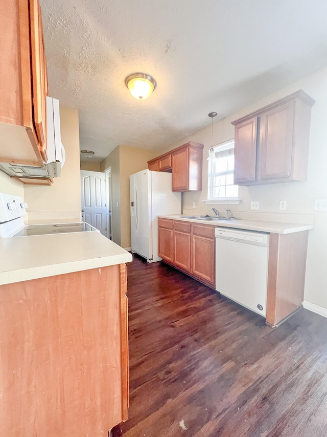 kitchen with sink, white appliances, dark wood-type flooring, decorative light fixtures, and kitchen peninsula