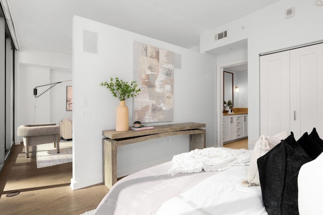 bedroom featuring ensuite bath, a closet, and light wood-type flooring