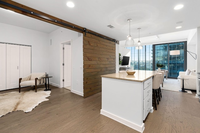 kitchen featuring dark hardwood / wood-style floors, pendant lighting, white cabinetry, a wall of windows, and a barn door