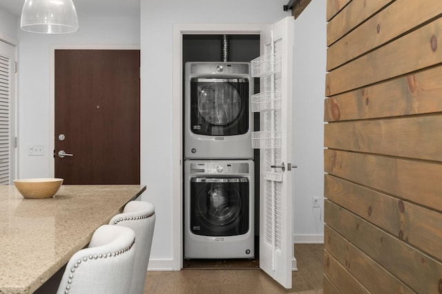 laundry area featuring stacked washer / drying machine and wood-type flooring