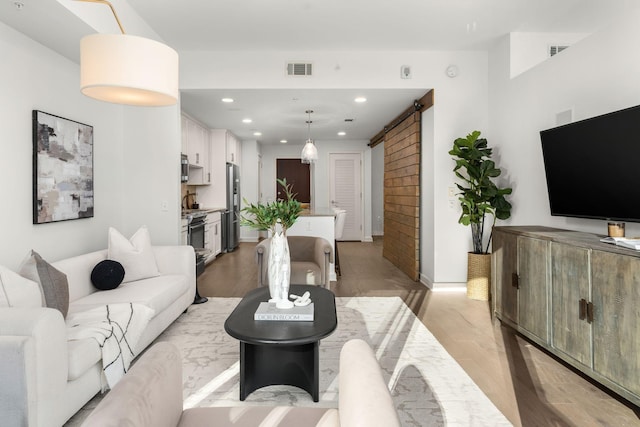 living room featuring a barn door and light hardwood / wood-style flooring