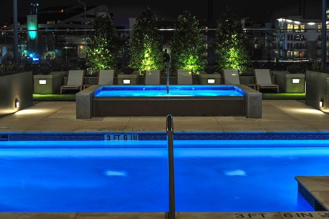 pool at night with a jacuzzi and a patio