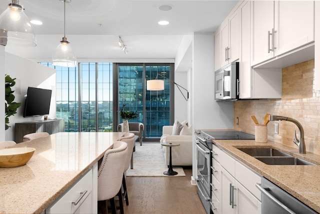 kitchen with sink, light stone counters, appliances with stainless steel finishes, decorative backsplash, and white cabinets