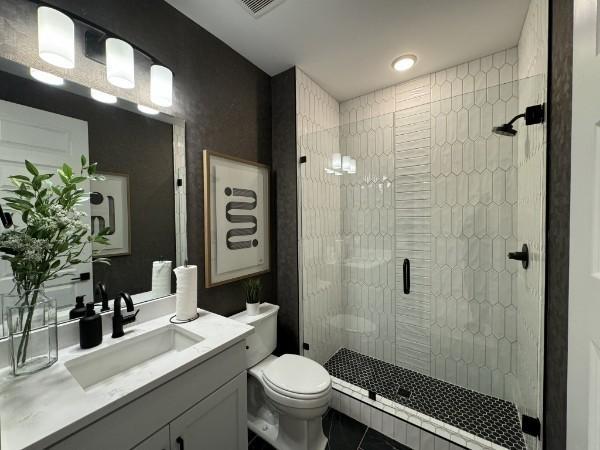 bathroom with vanity, a shower with shower door, tile patterned floors, and toilet