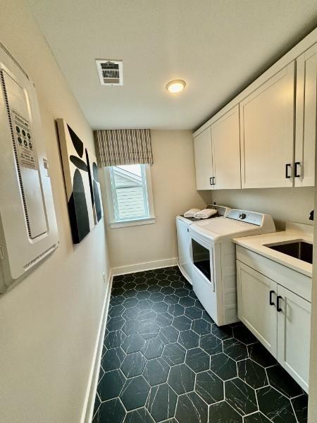 laundry area with sink, washing machine and dryer, and cabinets