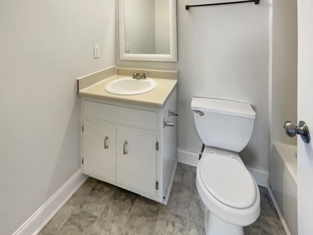 bathroom featuring vanity, a tub to relax in, and toilet