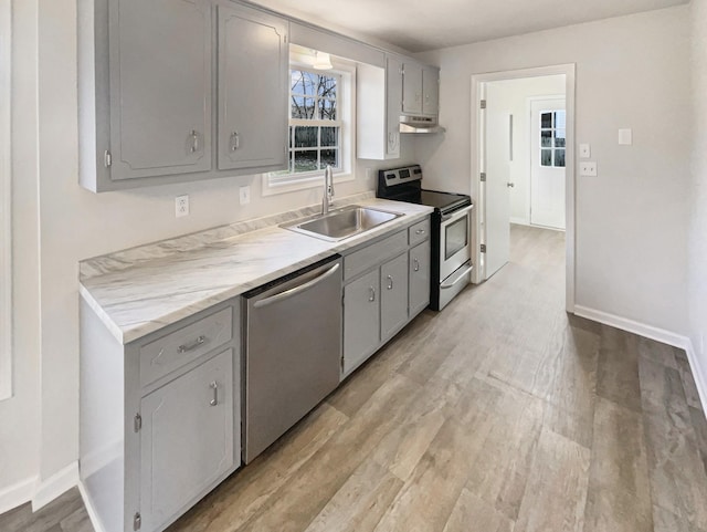 kitchen featuring stainless steel appliances, gray cabinets, sink, and light wood-type flooring