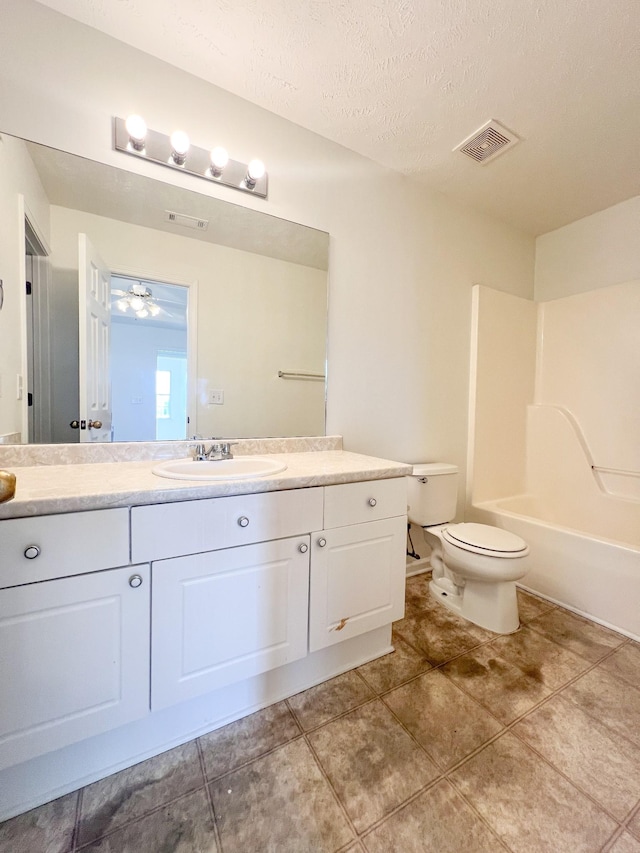 full bathroom with vanity, washtub / shower combination, a textured ceiling, and toilet