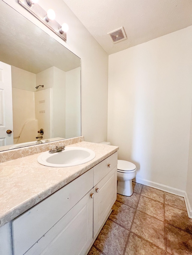 bathroom with walk in shower, vanity, toilet, and a textured ceiling