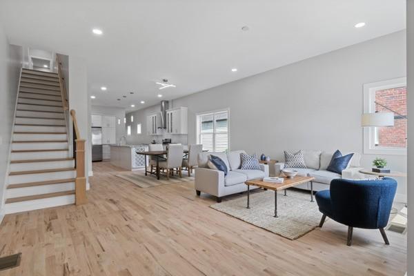 living room featuring recessed lighting, light wood-type flooring, and stairs