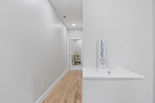 corridor featuring light wood-style flooring, visible vents, and baseboards