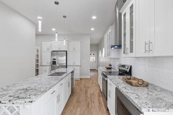 kitchen featuring white cabinetry, stainless steel appliances, decorative light fixtures, and an island with sink